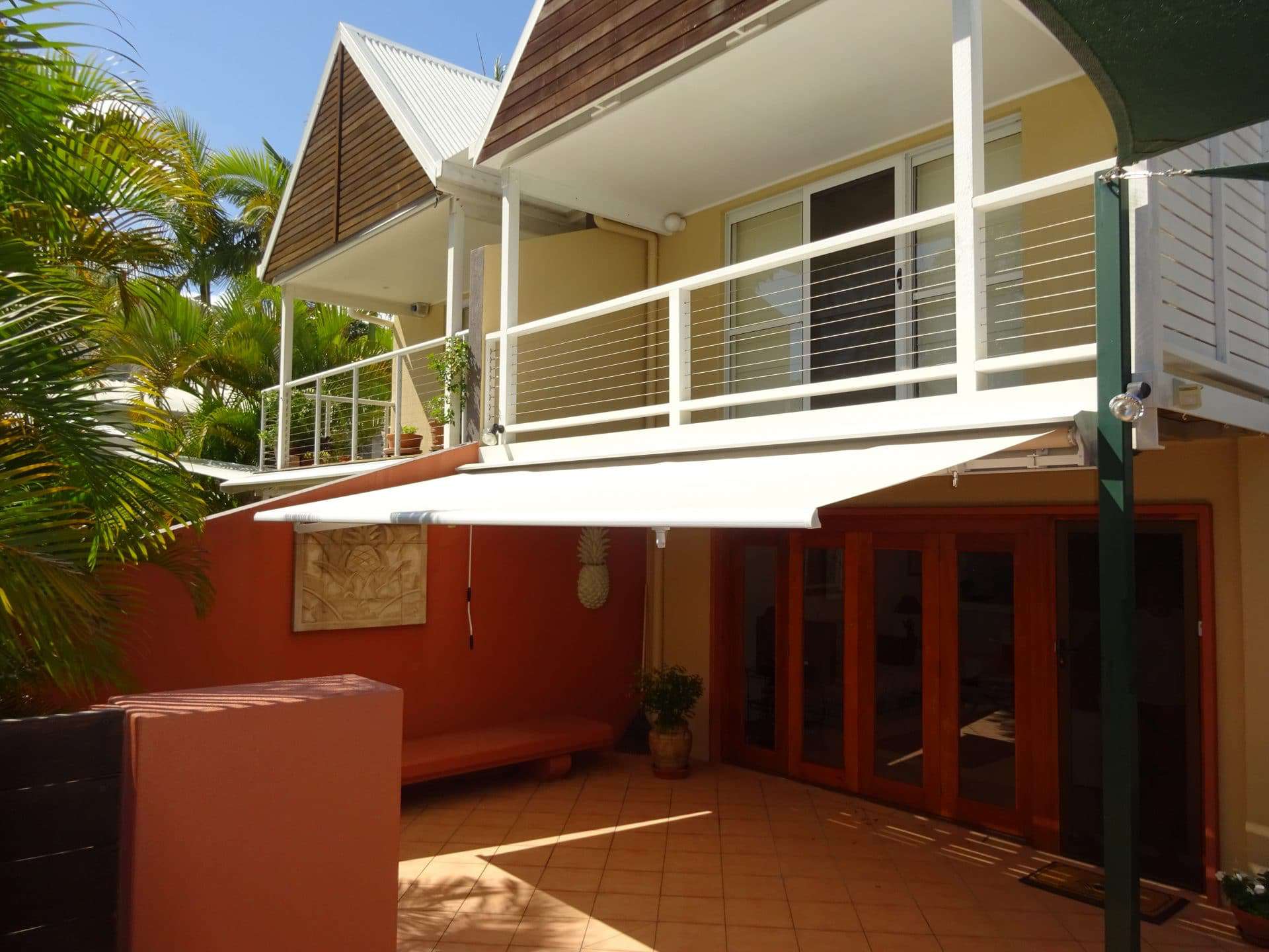 Folding Arm Awnings above patio area with balcony above