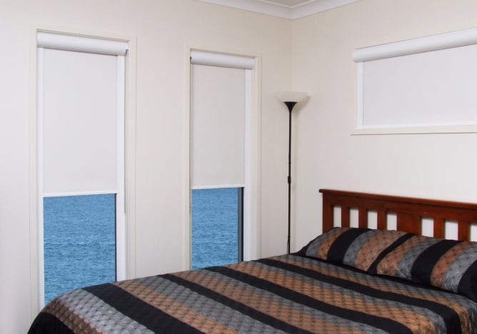 Roller Blinds in bedroom with wooden bed and stripy bed spread 