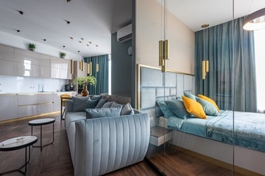 bedroom and lounge area in matching sage green tones with bed and yellow throw pillows